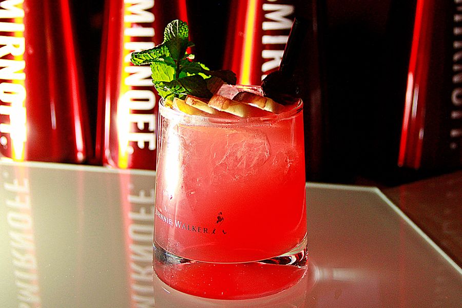 Roter Cocktail mit frischer Minze und Crushed Ice im Tumbler auf einer Bartheke