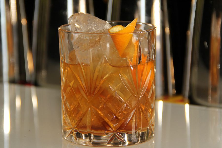 Old Fashioned im geschliffenen Kristallglas mit großem Eisstück und Orangenzeste