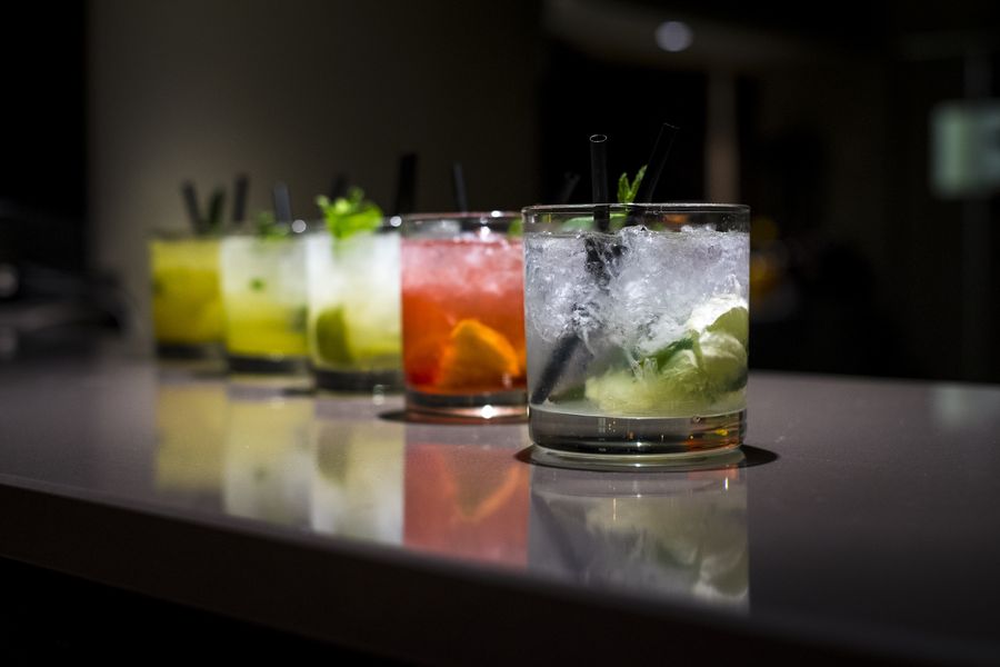 Fünf frisch zubereitete Drinks mit Crushed Ice, Minze und Limette auf einer dunklen Bartheke