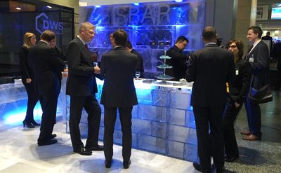 Beleuchtete Eisbar auf einem Messestand, davor Gäste im Gespräch